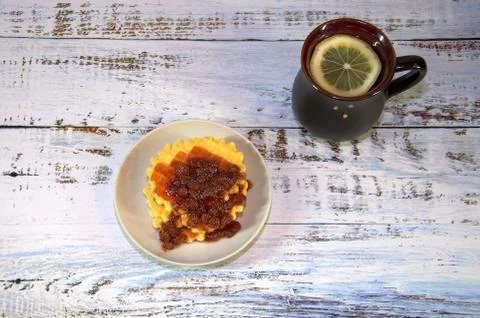 A black ceramic tea cup with a slice of lemon and a plate of Viennese waffles Stock Photos