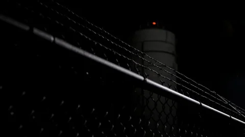 Black chain barbed wire link fence pan down night water tower.mov 動画素材 95760666