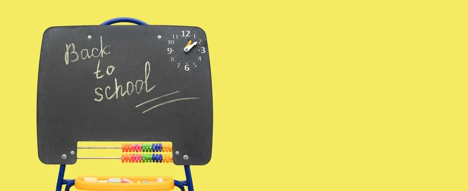 Black chalkboard with back to school note on yellow background. Stock Photos