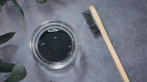 Black charcoal paste for teeth cleaning on a gray surface Stock Footage 341071370