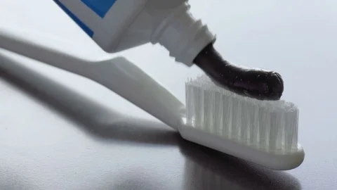 Black charcoal toothpaste is squeezed on a toothbrush Stock Footage 85215522