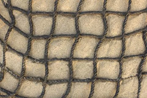 Black checkered rope net on light sand close up. natural surface texture Stock Photos