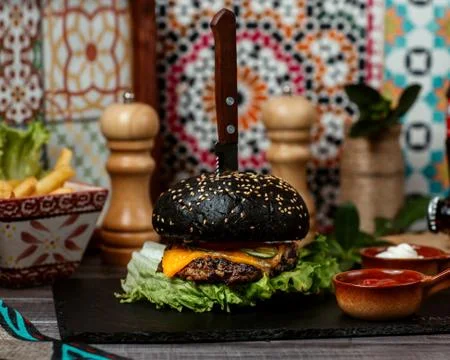 Black cheeseburger with knife inside Stock Photos