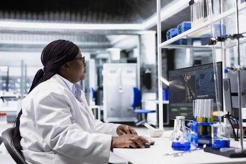 Black chemist working in biotechnology lab surrounded by modern tools Stock Photos