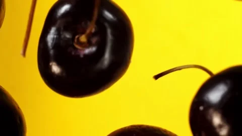 Black cherries fly on a yellow background closeup in slow motion Vídeos de archivo 151118809