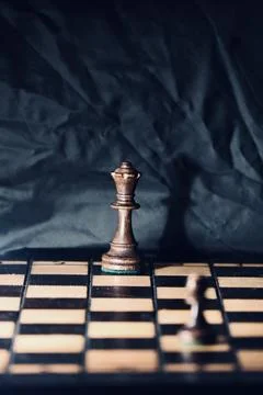 Black Chess Pawn Facing Queen in Strategic Showdown on Wooden Board Stock Photos