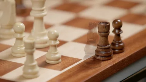 Black chess pieces being placed on wooden board in sequential order during .. Stock Footage 337622716