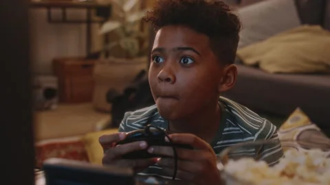 Black Child Devouring Popcorn and Playing Video Game on TV at Home Stock Footage 273740282