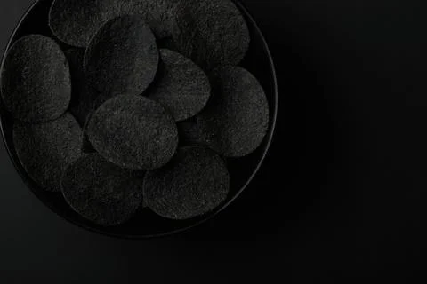 Black chips and red hot peppers on black background Stock Photos