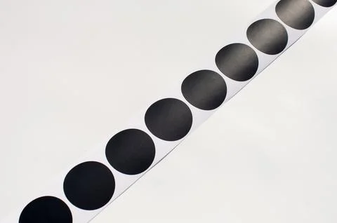 Black circular stickers on white surface in diagonal row design Stock Photos