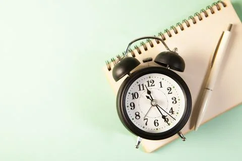 Black clock and notepad with white background Stock Photos