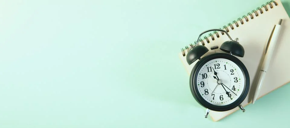 Black clock and notepad with white background Stock Photos