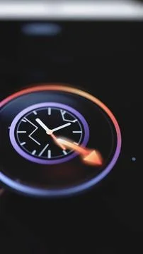 Black clock dial intersects bright orange arrow Stock Photos