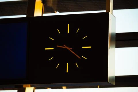 Black clock face with orange clock hands. Stock Photos