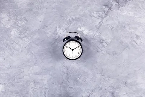 Black clock on grey concrete background. Stock Photos