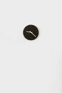 Black clock on white wall. Minimalist home interior design decoration. Time c Photos
