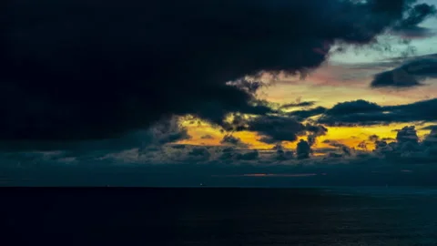 Black clouds quickly cover the sun and the sky over the sea at sunset Stock Footage 168476780