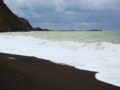 Black coarse sand on the shore of the mountain stormy sea Stock Footage 81968042