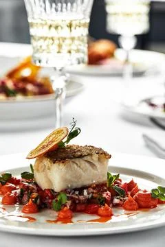 Black cod fillet on a vegetable stew, festive serving on a white grater on a Stock Photos