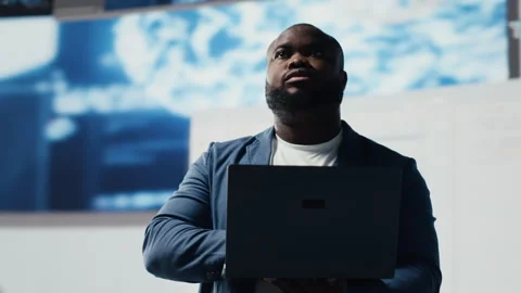 Black coder focused on programming with laptop in a high tech workspace Stock Footage 312359600
