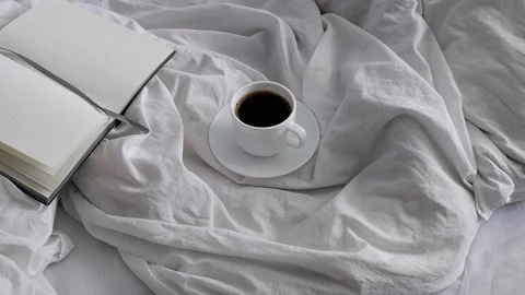 Black coffee and a notebook in a white bed. Interior. Cosiness. Stock Footage 159061672