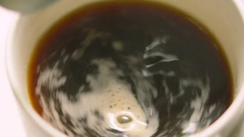 Black Coffee Being Stirred with Teaspoon Creating Small Frothy Vortex Stock Footage 336616582