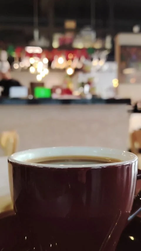 Black Coffee in Brown Ceramic Cup with Lush Green Plant Background Stock Footage 325746036