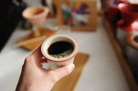Black coffee in cup in hand close up. Flavor wheel and origami dripper on Stock Photos