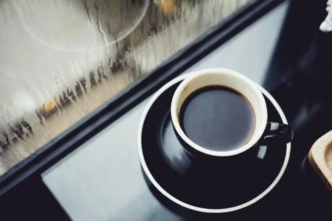 Black coffee cup on table in cafe restaurant near window when raining in gard Stock Photos