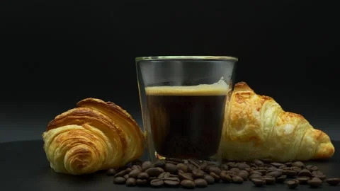 Black Coffee In Double Glass Wall And Croissant Rotating On Dark Background. Stock Footage 198110548