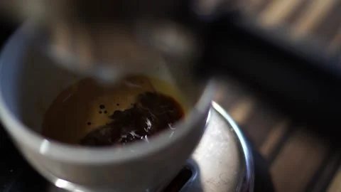 Black coffee dripping from a coffee maker horn into a cup on a tray Video stock 283550870