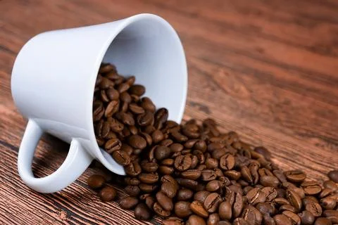 Black coffee foil packaging bag on wooden table top view. Spilled beans fla.. Stock Photos