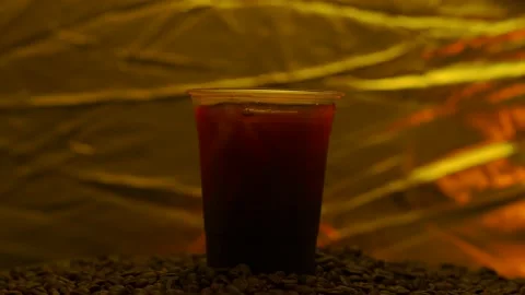 Black Coffee Iced In Disposable Plastic Cup Rotated Against Gold Background. Stockbeeldmateriaal 196776410