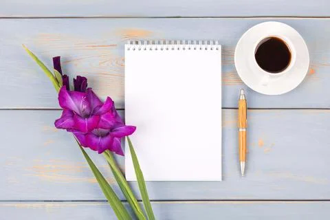 Black coffee, notebook and gladiolus flower Stock Photos