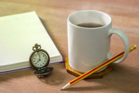 Black coffee with a notebook on a brown table. Stock Photos