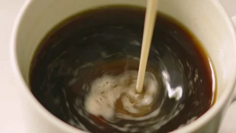 Black Coffee Spinning in Slow Motion as Oat Milk is Added Stock Footage 336616873