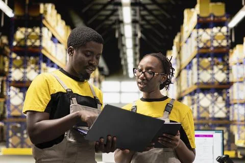 Black colleagues preparing orders in boxes for shipment in large warehouse Foto stock