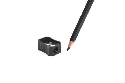 Black colored plastic pencil sharpener and a black wood pencil placed beside Stock Photos