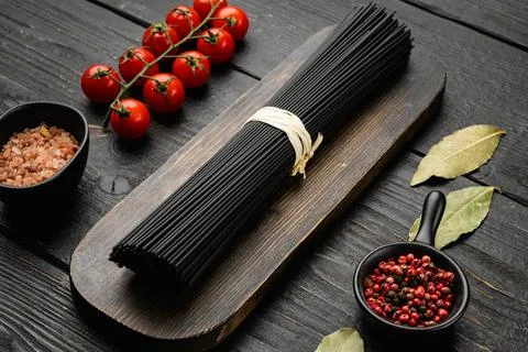 Black colored spaghetti raw dry, on black wooden table background Stock Photos
