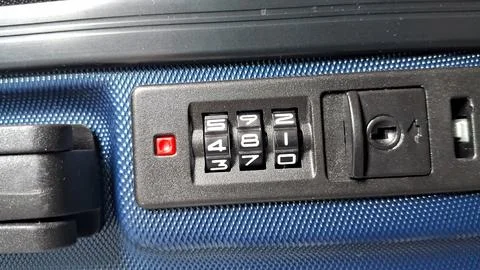 Black combination lock with white numbers on blue textured suitcase 库存照片