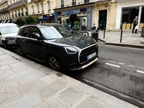 Black compact Mini Cooper S parked on a Paris, France street outside shops .. 스톡 사진