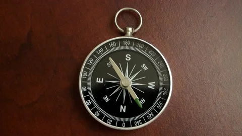 Black compass on wooden table with rotating pointer. Stock Footage 154992013