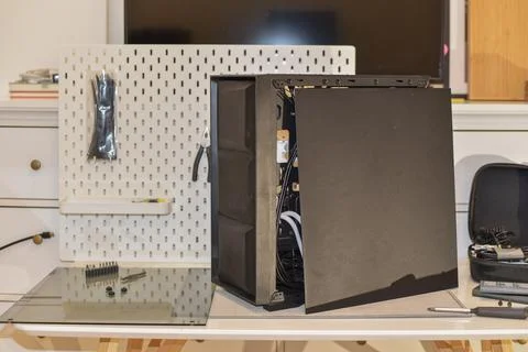 Black computer case open on desk with internal components wiring tools Foto stock