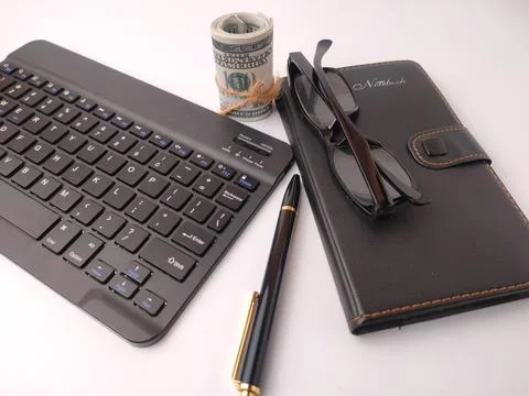 A black computer keyboard, a black leather notebook with eyeglasses, a pen,.. Stock Photos