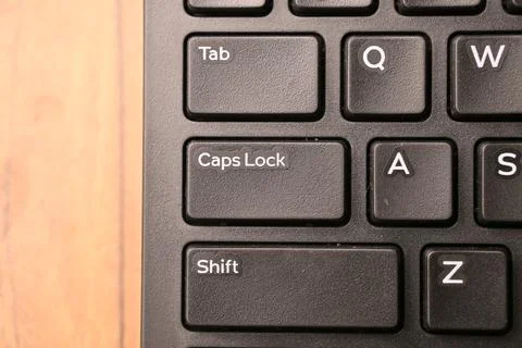 Black Computer Keyboard Macro Shot Highlighting Caps Lock Key with Soft Blu.. Foto stock