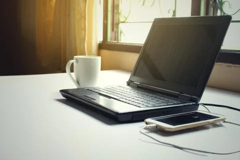 Black computer laptop notebook pc on working table with white coffee cup and Stock Photos