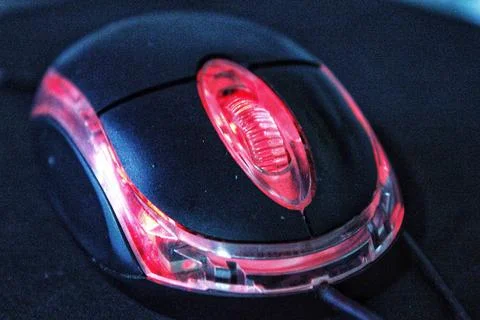 Black computer mouse with red light on dark background Фото