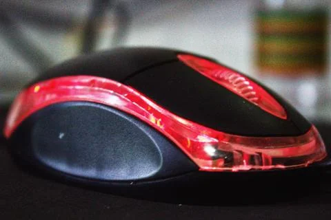 Black computer mouse with red light on blurred background Foto stock
