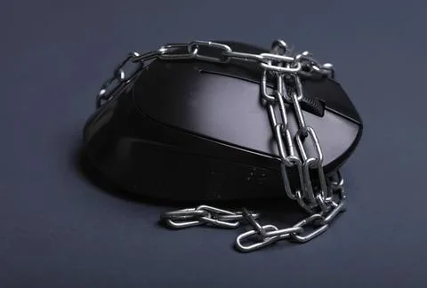 Black computer mouse wrapped in metal chain on dark background Stock Photos
