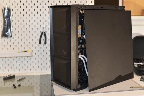 Black computer tower case open exposing internal components on workbench Foto stock
